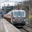 Freight train passing through a European station in early spring.